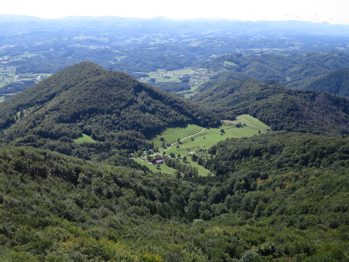 Pogled z vrha Boča proti Celjski kotlini in na travnik s planinskim domom